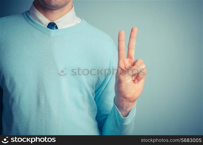 A young man is gesturing a peace sign