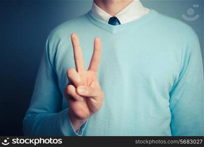 A young man is gesturing a peace sign