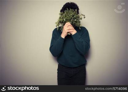 A young man is hiding behind a big bunch of parsley