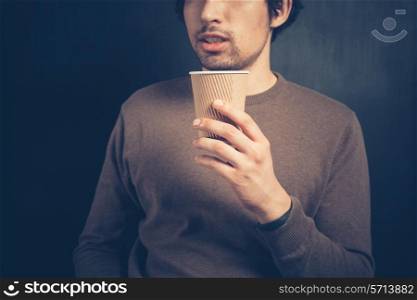 A young man is holding a brown paper cup