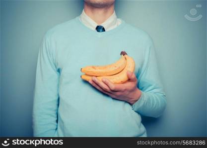 A young man is holding a bunch of bananas