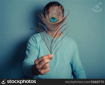 A young man is holding a pretty peacock feather