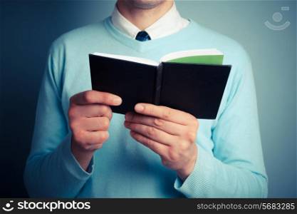 A young man is holding an open notebook
