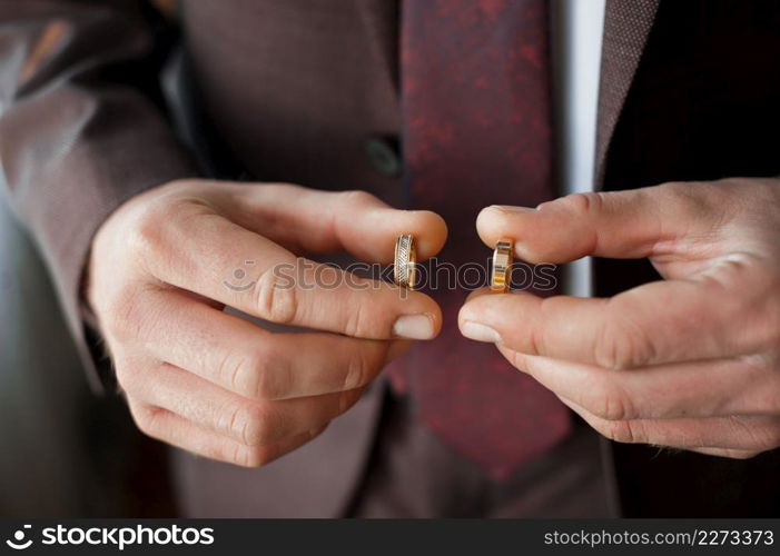 A young man is holding gold wedding rings in his hands.. Two gold wedding rings in mens hands 4129.