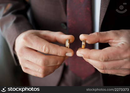 A young man is holding gold wedding rings in his hands.. Two gold wedding rings in mens hands 4129.