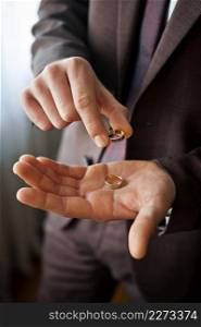 A young man is holding gold wedding rings in his hands.. Two gold wedding rings in mens hands 4130.