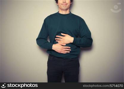 A young man is rubbing his stomach