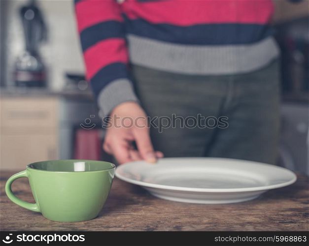 A young man is setting the table in a kitchen with a plate