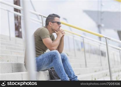 A young man is sitting on the stairs and sad