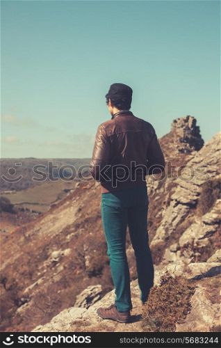 A young man is standing in the mountains and admiring the view