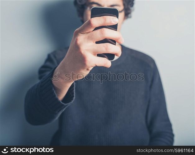 A young man is taking a selfie of himself using his smartphone
