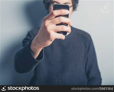 A young man is taking a selfie of himself using his smartphone