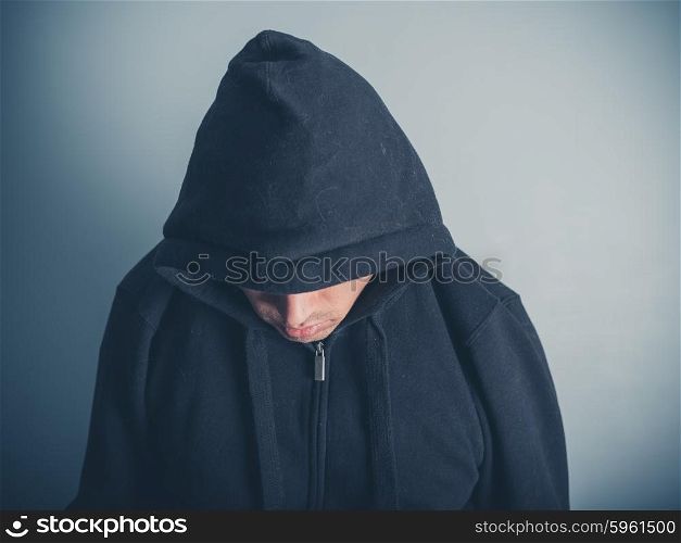 A young man is wearing a hooded top and is looking down