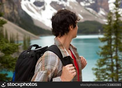 A young man looking out on a beautiful lake and mountain landscape