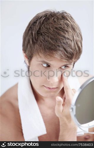 A young man looks in the mirror in the bathroom