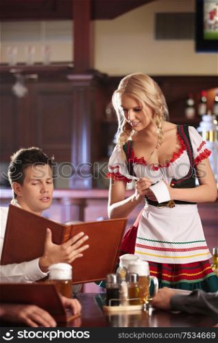 A young man makes an order to the waitress at the pub