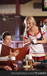 A young man makes an order to the waitress at the pub