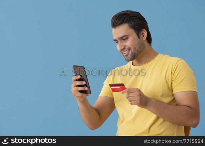 A young man making online payment with credit card and mobile.