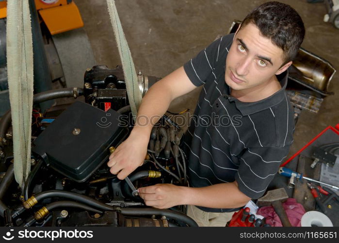 A young man mechanic repairing motor boats and other