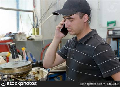a young man mechanic repairing motor boats and phone at customer