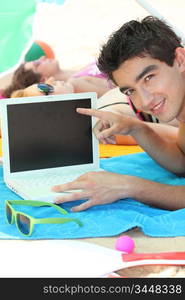 a young man on the beach showing a computer