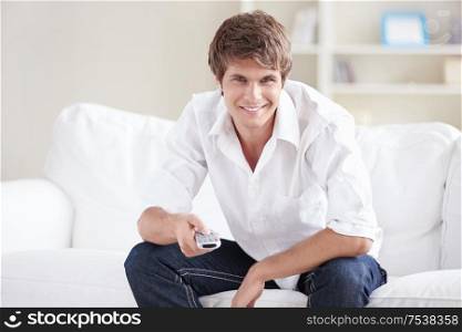 A young man on the couch switches remote control TV channels