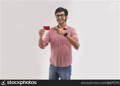 A young man pointing towards his credit card.