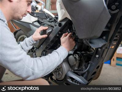 a young man repairing the motorcycle