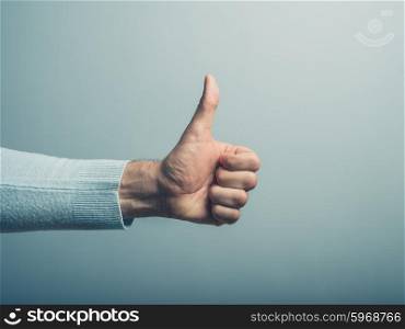 A young man&rsquo; hand is displaying a thumbs up, indicating that he likes or approves of something