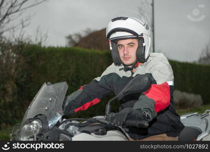 a young man sits on a motorcycle and has a helmet on his head