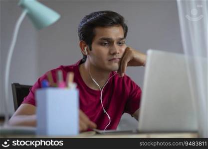 A YOUNG MAN SITTING TIRED WHILE ATTENDING ONLINE CLASS