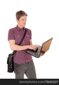 A young man standing isolated for white background holding hislaptop and working on with his briefcase over his shoulder.