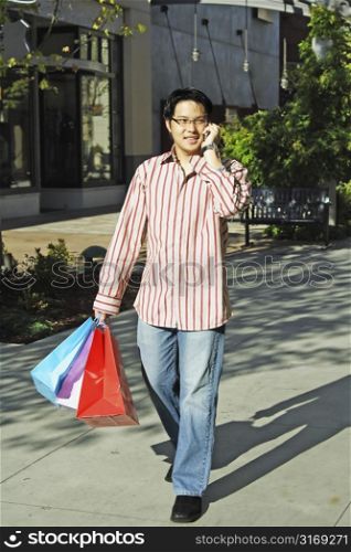 A young man talking on the phone while shopping at an outdoor mall