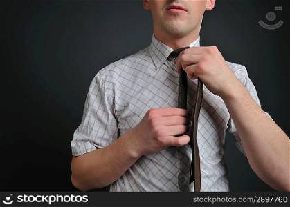 a young man tying his brown tie