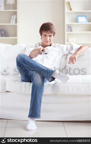 A young man watching TV on the couch