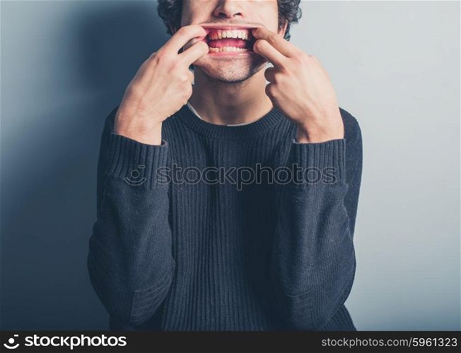 A young man wearing a black sweater is pulling silly faces
