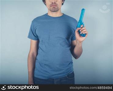 A young man wearing a blue t-shirt is holding a water pistol
