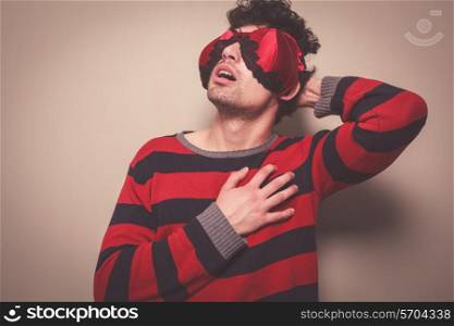 A young man wearing a bra on his face is touching his chest