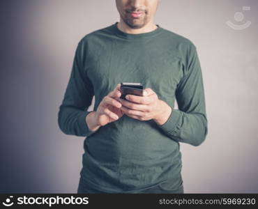 A young man wearing a green top is using a smart phone