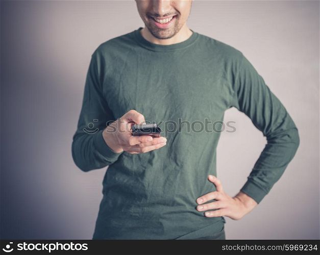 A young man wearing a green top is using a smart phone