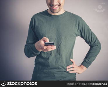 A young man wearing a green top is using a smart phone