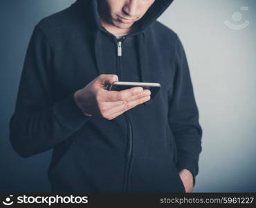 A young man wearing a hooded top is using his smartphone