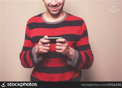 A young man wearing a striped jumper is using his smart phone