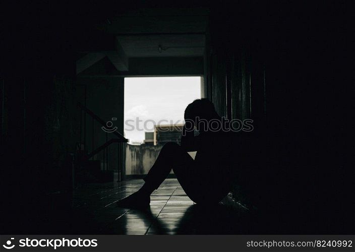 A young man who is exhausted from life’s problems. with a feeling of depression and stress sitting on a dark corridor Bad and unhappy life concept