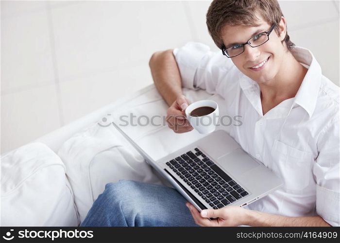 A young man with a cup and laptop