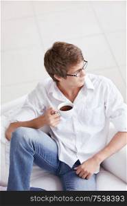 A young man with a cup of coffee on the couch