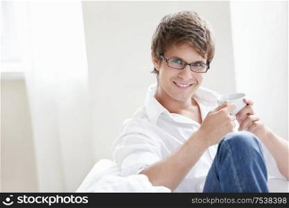 A young man with a cup of coffee on the couch