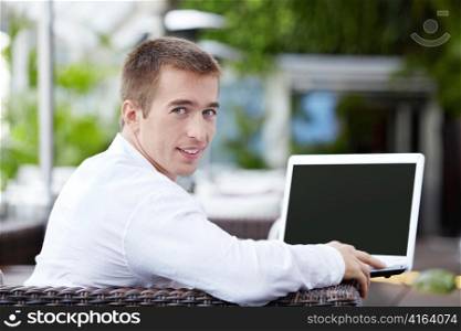 A young man with a laptop in a restaurant
