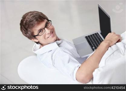 A young man with a laptop on a couch