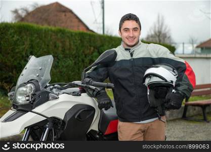 a young man with motorcycle and holding white helmet